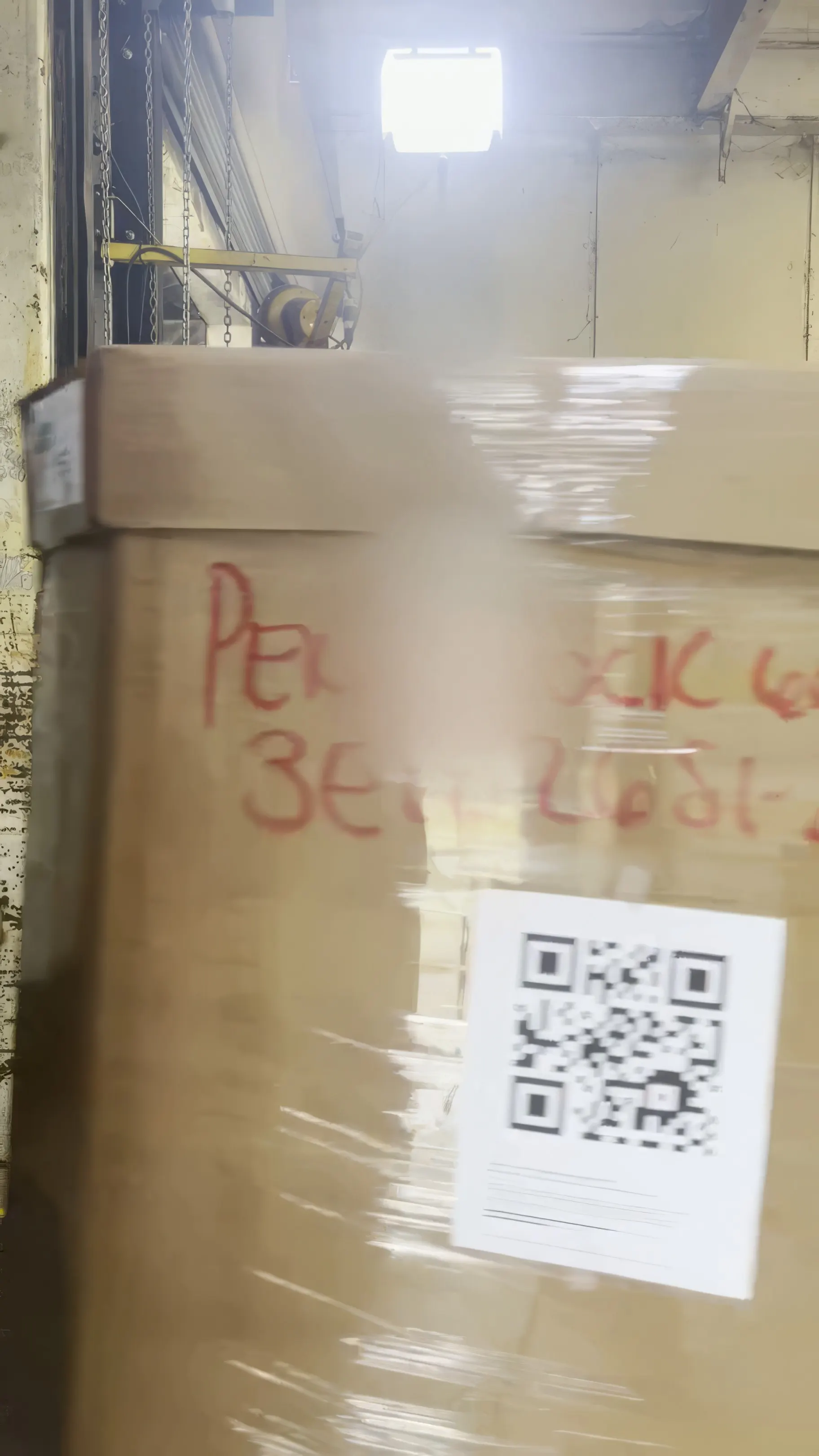 A shrink-wrapped pallet crossing the dock door, its shipping label square to the camera in the captured frame
